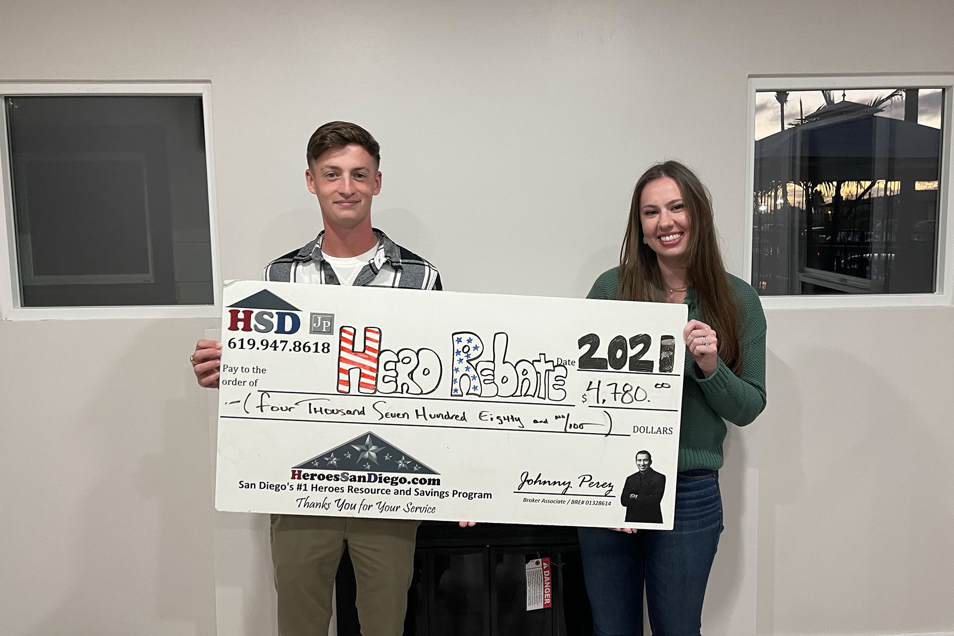 Man and woman standing together and holding a Hero Rebate check for $4,780.