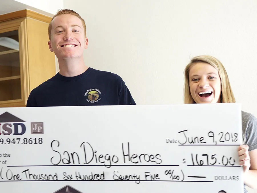 Man and woman holding a giant check made out to San Diego Heroes for the amount of $1,675.